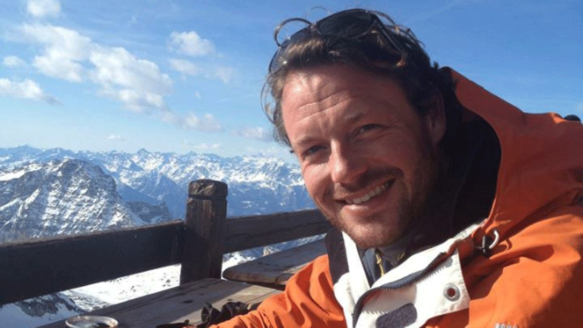 En mand der sidder og kigger ud over alperne